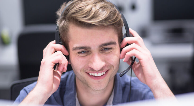 young smiling male call centre operator doing his job with a headset